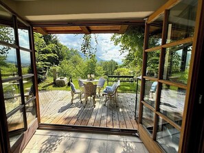 Una terrazza scoperta con tavolo e sedie, immersa nel verde e con vista sulle montagne.