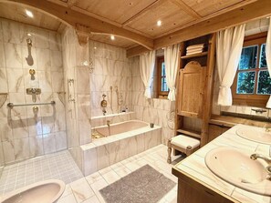 A bathroom with a bathtub, two sinks, a vanity, and a shower area. - Charming Tyrolean penthouse in an enchanting location near Kitzbühel (Sankt Johann in Tirol)