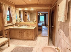 A wooden cabin-style bathroom with a large vanity, a bathtub, and a shower area. - KitzDiamant with Pool & Sauna by Belle-Stay (Sankt Johann in Tirol)