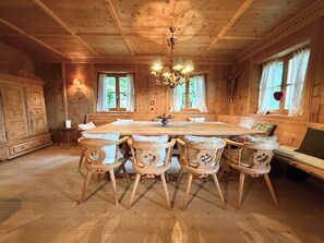 A wooden dining room with a large table and chairs, a chandelier, and a crucifix on the wall. - Charming Tyrolean penthouse in an enchanting location near Kitzbühel (Sankt Johann in Tirol)