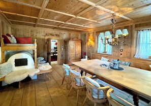 A wooden interior with a fireplace, dining table, chairs, and a chandelier. - Charming Tyrolean penthouse in an enchanting location near Kitzbühel (Sankt Johann in Tirol)