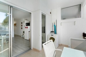 Een modern appartement met een schuifdeur naar een balkon, een wasmachine en een kleine kitchenette.