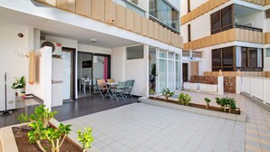 Un edificio moderno con patio, mobiliario exterior y un pequeño jardín.