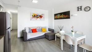 Una sala de estar moderna con sofá, mesa de comedor, sillas, refrigerador y obras de arte en las paredes.