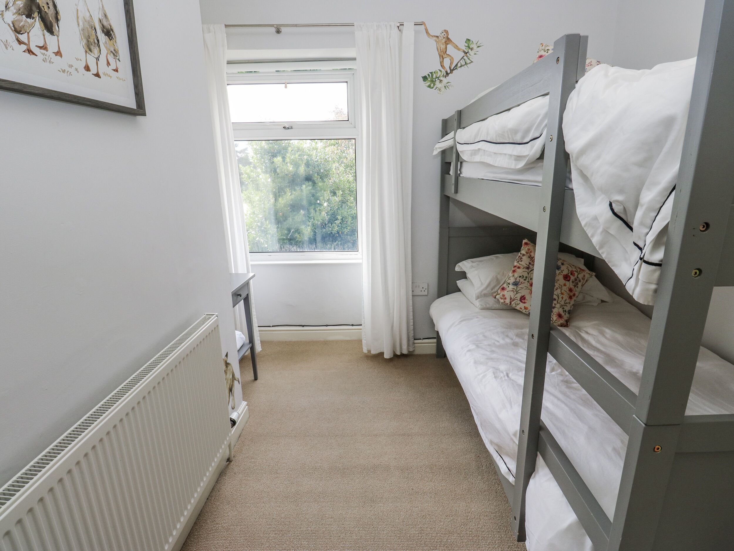A room with bunk beds, a radiator, a window with curtains, and a small table.