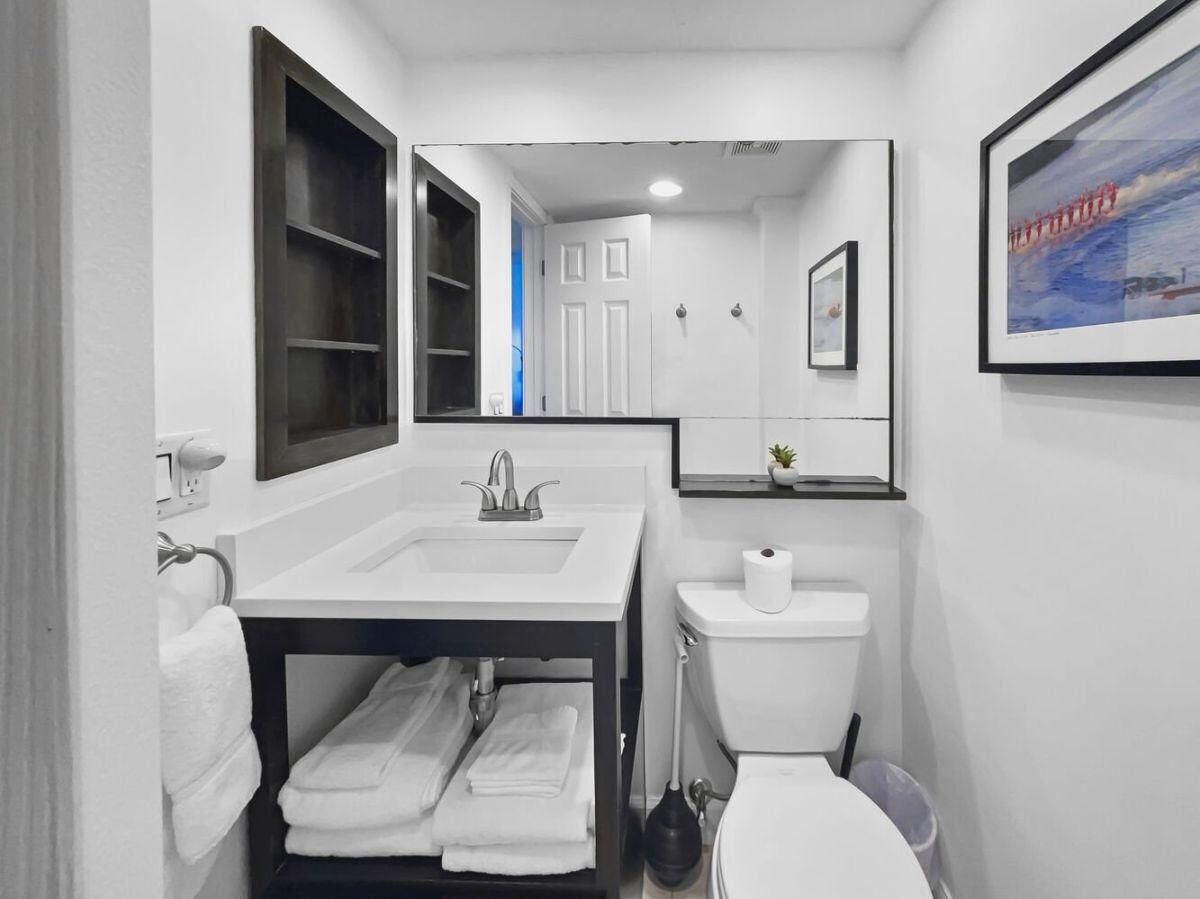 A modern bathroom with a white sink, mirror, and toilet.