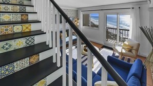 A staircase with colorful tiles, a blue sofa, and a view of the ocean.