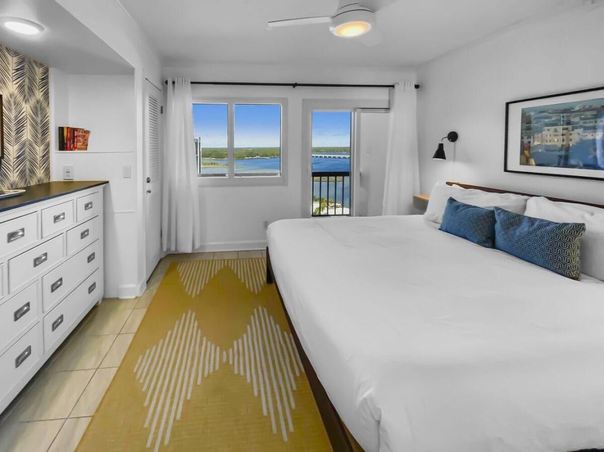Un dormitorio con una cama grande, un aparador, una ventana con vista a un puente y un ventilador de techo.