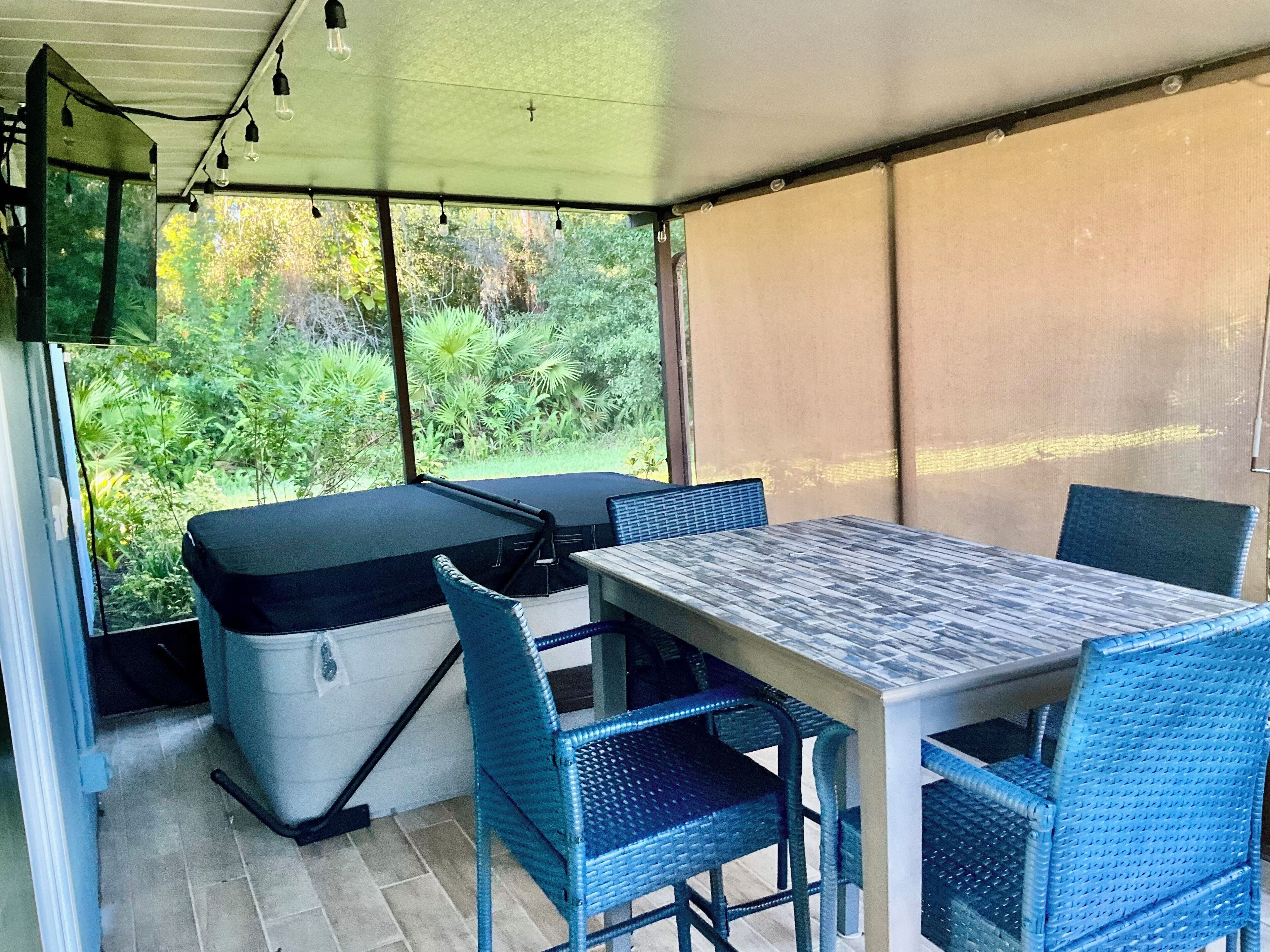 Un patio couvert comprenant une table et des chaises, un canapé et une vue sur la verdure environnante.