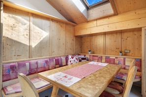 Un intérieur en bois avec un plafond haut, une lucarne et un banc agrémenté de coussins colorés.