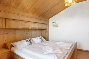 Une pièce aux murs lambrés, comprenant un lit, une table de chevet et un luminaire fixé au mur.