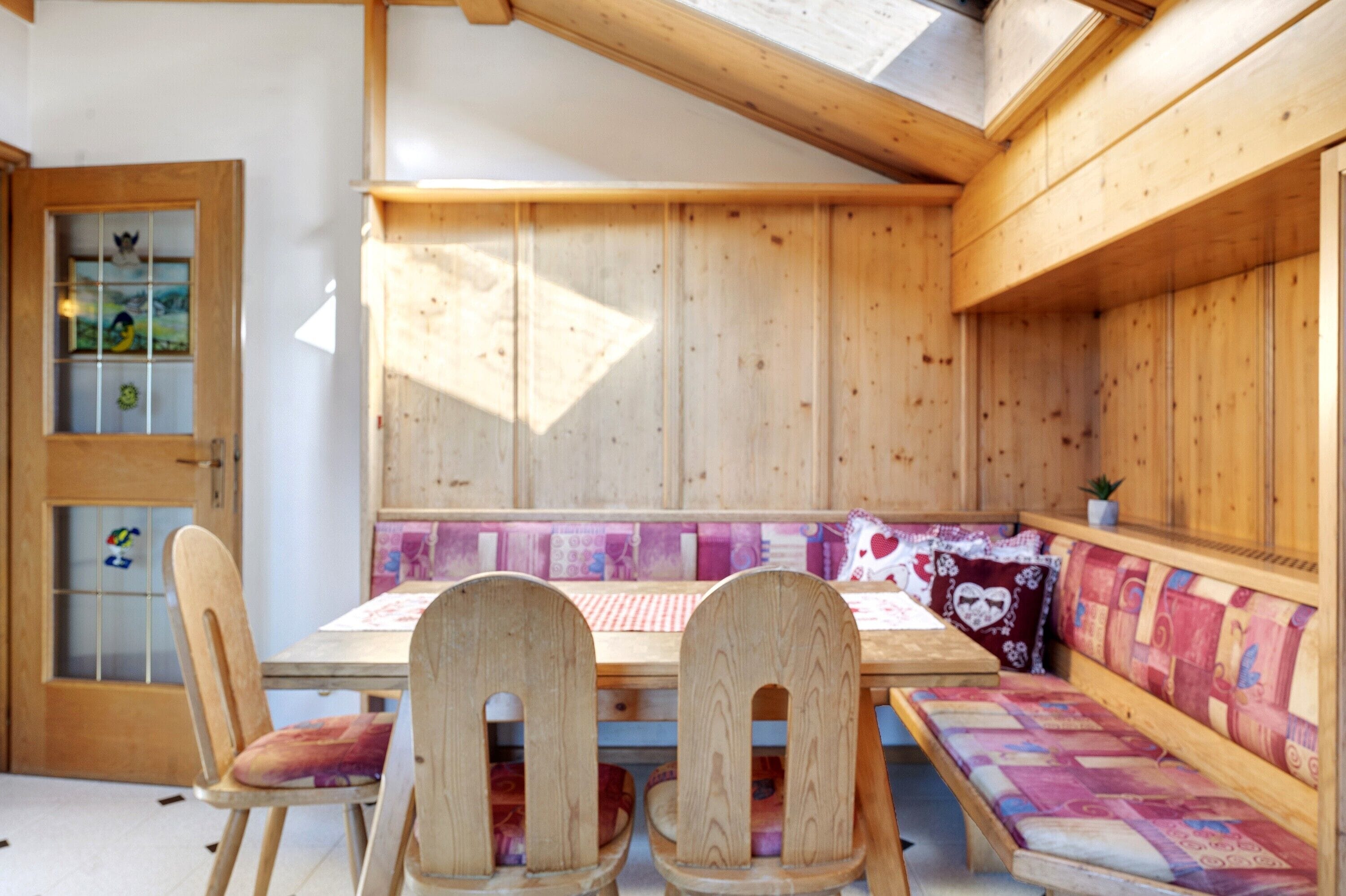 A wooden interior with a bench, chairs, and a table.