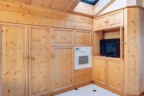 Une cuisine avec des meubles en bois, un four encastré et un four à micro-ondes.