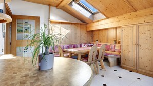 Un intérieur en bois avec une table ronde, des bancs et une lucarne.