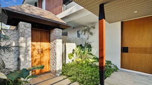 Una casa moderna con fachada de piedra, puerta de madera y escalera que lleva a la entrada.
