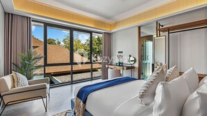 Una habitación de hotel moderna con una cama grande, un escritorio, una silla y vistas al exterior.