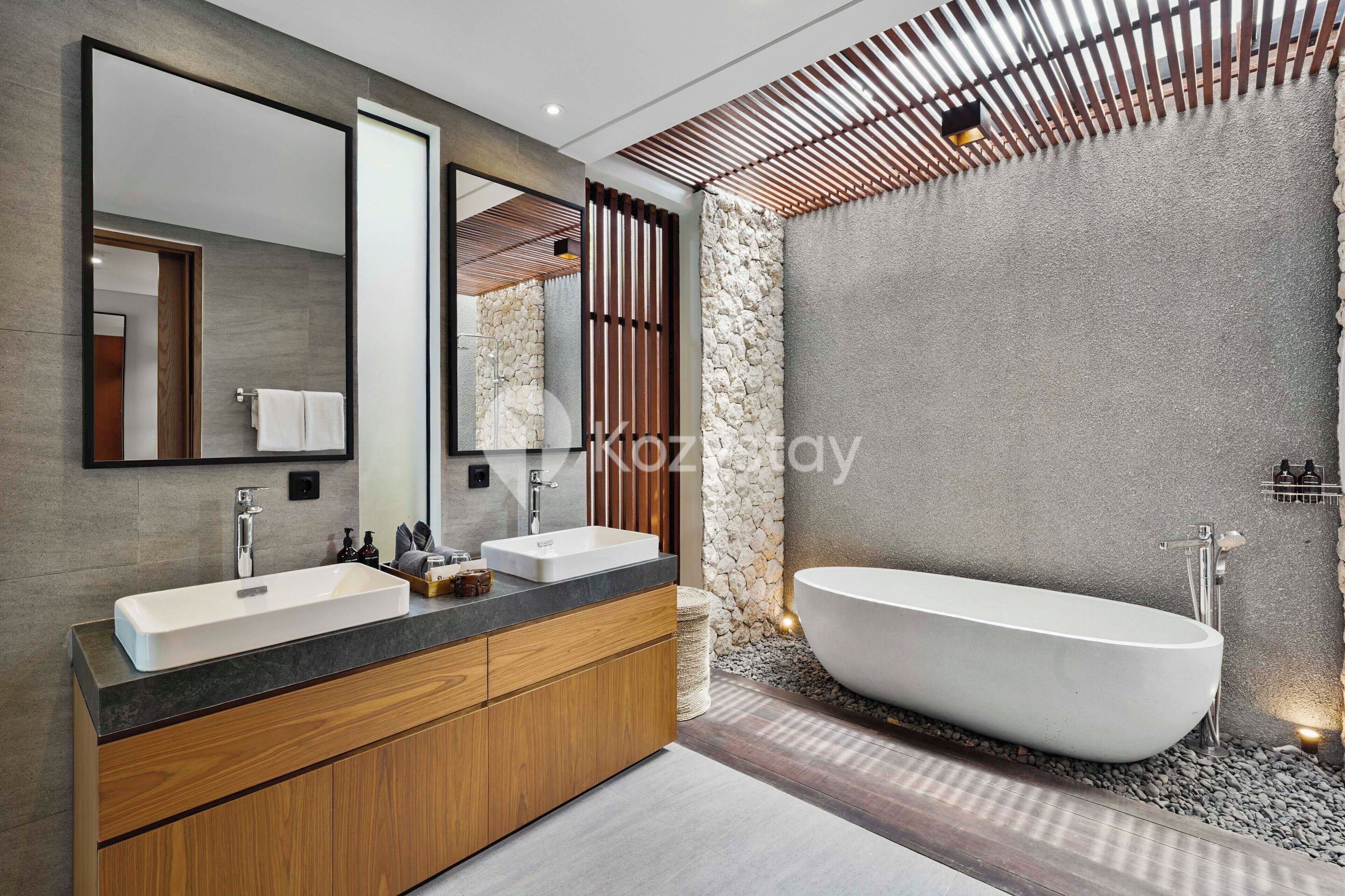 A modern bathroom with a freestanding bathtub, two sinks, and a large mirror.