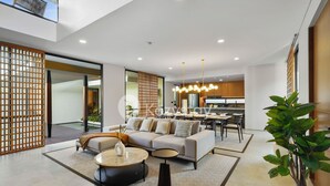 Una sala moderna con un sofá, una mesa de centro y un comedor al fondo.