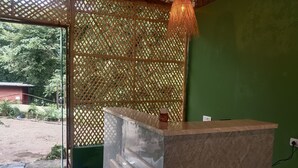 A reception desk with a green wall and a wooden lattice partition. - Pennylane Hotel (Rishikesh)