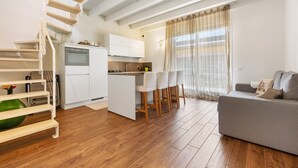 Una cocina moderna con armarios blancos, horno empotrado y comedor con mesa y sillas.