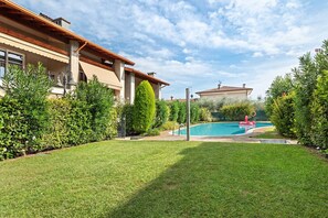 A residential property with a swimming pool, well-maintained lawn, and mature landscaping.