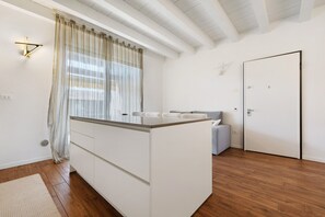 A modern kitchen with a central island, a dining area with a sofa, and a door.