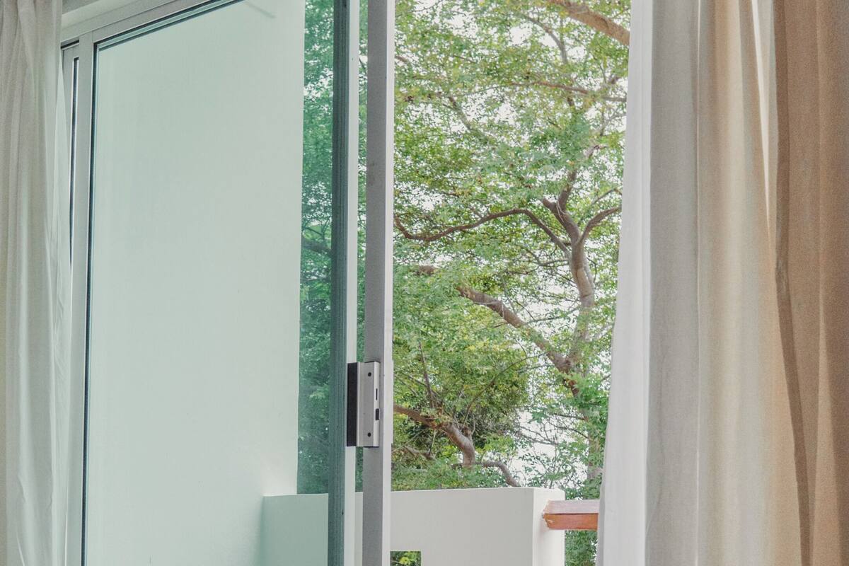 A room with a sliding glass door leading to an outdoor area with a tree.