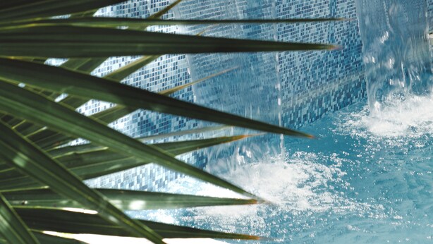 A pool with a waterfall feature, surrounded by palm leaves. - Lifestyle Hotel Juquilita (Puerto Escondido)