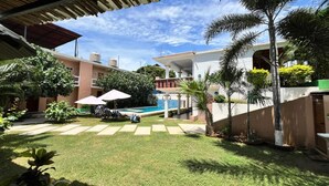A well-maintained courtyard with a swimming pool, palm trees, and a covered seating area. - Lifestyle Hotel Juquilita (Puerto Escondido)