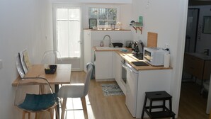 Une cuisine compacte comprenant un coin repas, un four à micro-ondes, un évier et un petit tabouret.