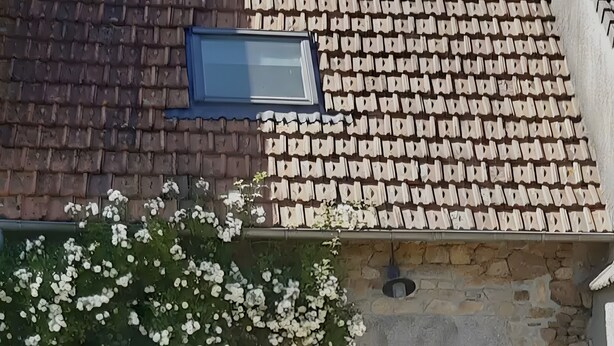 Une maison en pierre avec un toit en tuiles, une porte et une fenêtre.