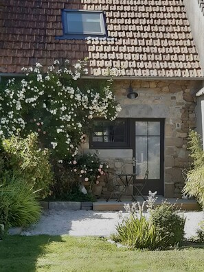 A stone house with a tiled roof, a door, and a window.