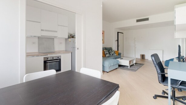 Un apartamento moderno con cocina, comedor y sala de estar con sofá y escritorio.