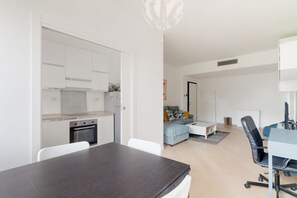 A modern apartment with a kitchen, dining area, and a living room with a sofa and a desk.