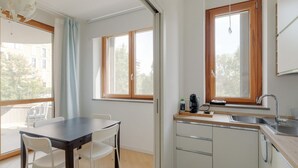 Una cocina compacta con ventana, una mesa de comedor con sillas y una pequeña encimera con un lavamanos.