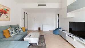 Una sala de estar moderna con sofá, mesa de centro, televisor y un cuadro grande.
