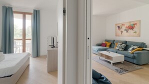 Un dormitorio moderno con una cama, un escritorio y vistas a un balcón.