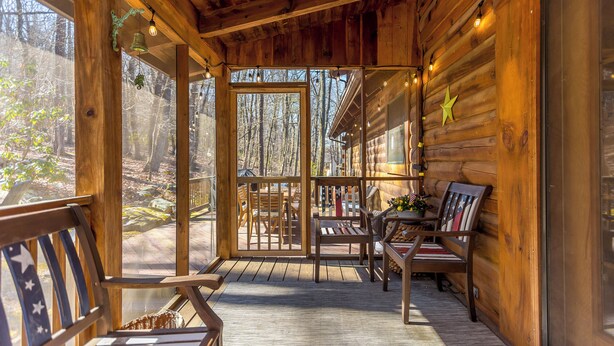 A wooden cabin with a porch, wooden furniture, and a star decoration.