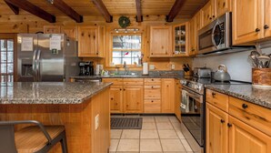 A kitchen with wooden cabinets, granite countertops, stainless steel appliances, and a large island with seating.
