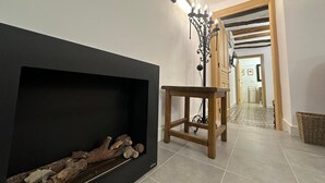 Un pasillo con chimenea, una mesa de madera y una araña.