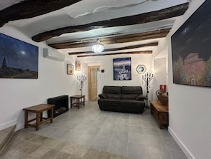 A living room with a sofa, a wooden bench, a candelabra, and a painting on the wall.