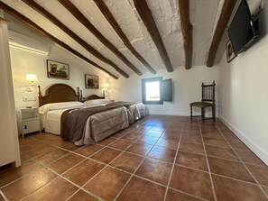 A bedroom with a large bed, a nightstand, a chair, and a window.