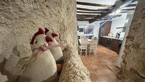 Un interior rústico con una pared de piedra, un banco de madera y una zona de comedor con sillas y una mesa.