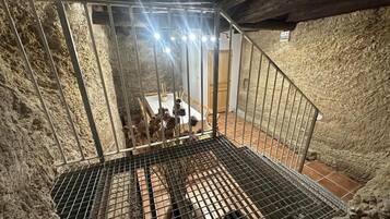 Eine Metalltreppe mit Metallgeländer führt zu einem Raum mit gefliestem Boden und einem Tisch mit Stühlen.