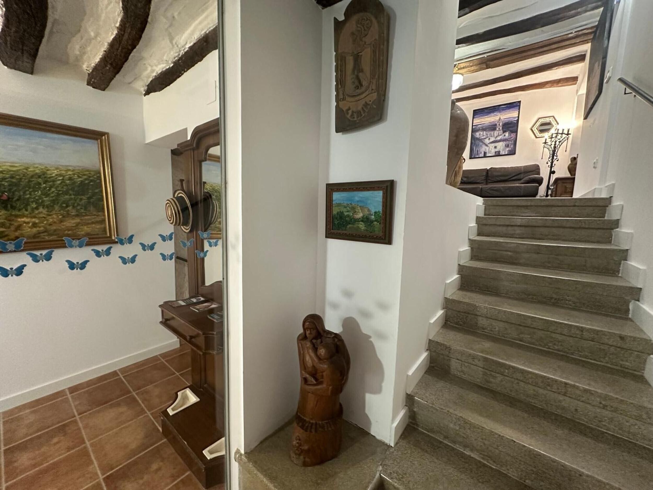 Una escalera con barandilla de madera, un perchero de pared y un cuadro enmarcado encima.