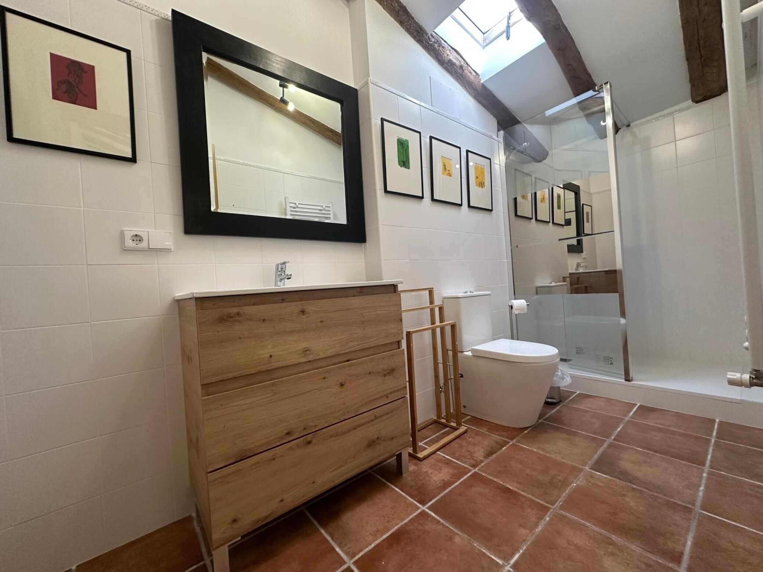 A bathroom with a wooden vanity, a large mirror, and a shower area.