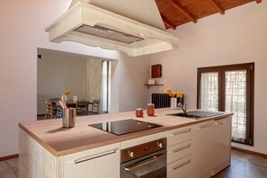 Une cuisine moderne dotée d’un plan de travail en bois, d’un four encastré et d’une grande fenêtre agrémentée de rideaux décoratifs.