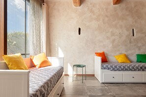 Una camera da letto moderna con due letti, uno sgabello e una finestra con tende.