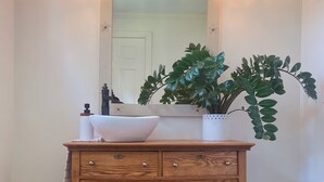 A wooden vanity with a white sink, two hanging pendant lights, and a large mirror above it. - Charming 3-bedroom house in Gouverneur with private basketball court. (Gouverneur)