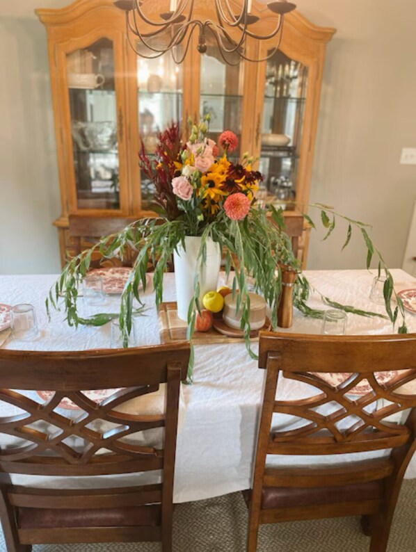 A dining table set with chairs, a floral centerpiece, and a wooden cabinet in the background.